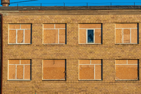Facade of a building with windows covered with OSB boards after the glass was brokenの写真素材