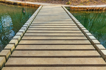 Concrete low footbridge on a stream or small river. Construction of a modern pedestrian bridge made of rectangular concrete blocksの写真素材