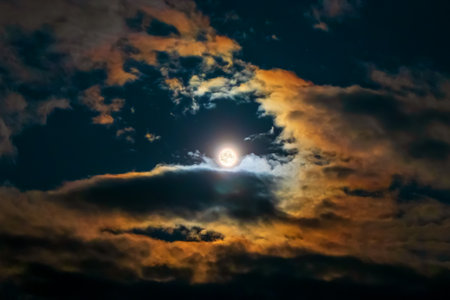 Full moon surrounded by colorful glowing clouds in beautiful night sky. Plural coronae, Lunar aureoleの写真素材