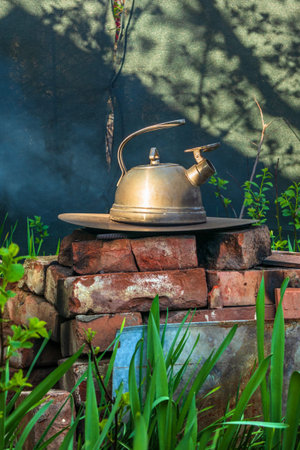 Steel kettle on a homemade brick stove outside. The rustic old way to boil water and cook food over...
