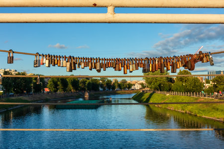 Padlocks hang from a rope on a bridge over a river in the city. Romantic padlocksの写真素材