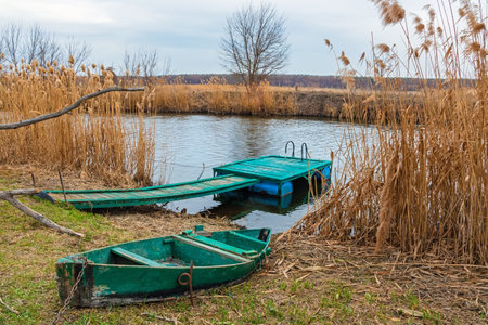 Wooden old rowing boat on the shore and pier on the small river Siversky Donets in Kharkiv region, Ukraineの写真素材