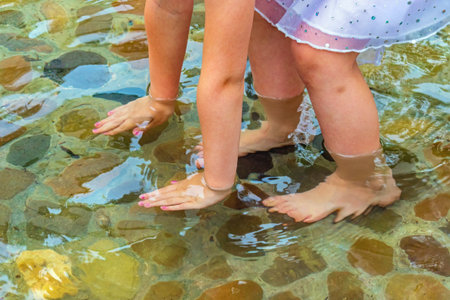 Children's feet and hands in water. Hardening the body in cold water can strengthen human immunityの写真素材