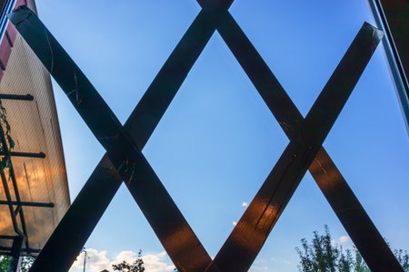 Dark tape is pasted in a cross on the glass. The tape is pasted on the window to protect the glass from the shock wave. View from indoors to blue skyの写真素材
