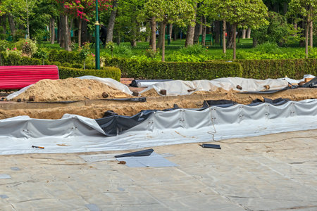 Construction of a large artificial pond in a park or city garden. Repair of an artificial pond with a waterproof coating on the bottomの写真素材