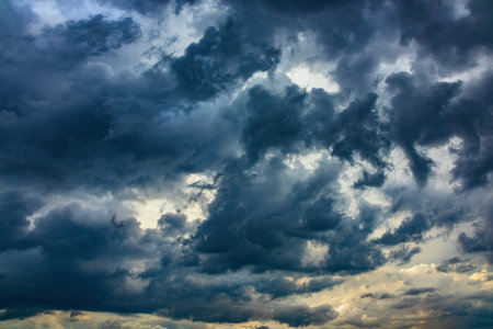 Dramatic sky with thick dark thunderclouds before a storm. Light breaks through the rain cloudsの写真素材