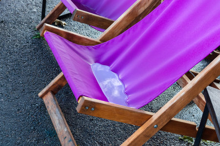 Water in wood-framed and fabric deckchair after rainの写真素材