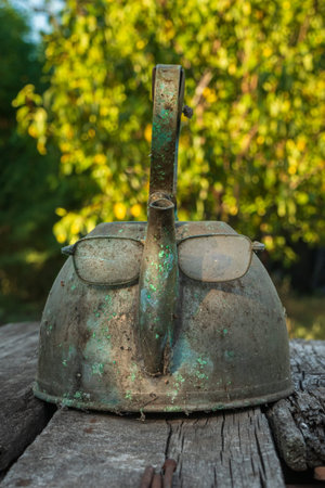 Glasses and an old vintage metal teapot look like a face. Example of Apophenia and pareidolia