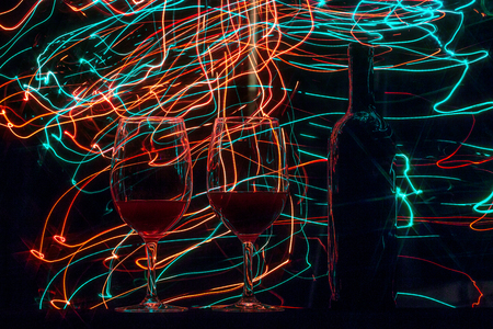 Glasses and wine bottle on black background and trailsの写真素材