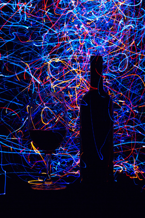 Glasses and wine bottle on black background and trailsの写真素材