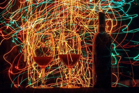 Glasses and wine bottle on black background and trailsの写真素材