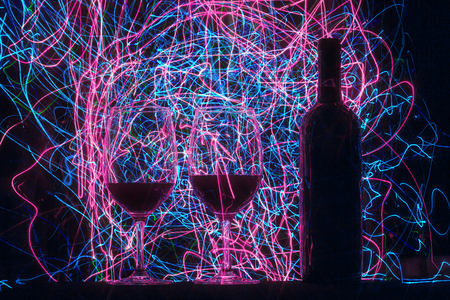 Glasses and wine bottle on black background and trailsの写真素材