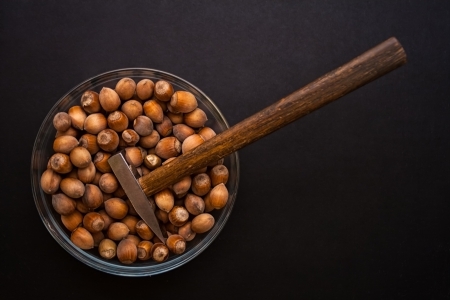 Nuts in glass bowl with hammerの写真素材