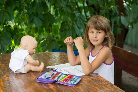Girl makes lessons sitting at a table in the gardenの写真素材