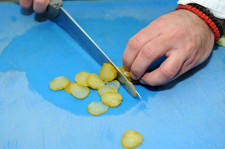 Chef cuts cucumber with knife on the board.の写真素材