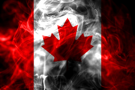 National flag of Canada made from colored smoke isolated on black background. Abstract silky wave background.の写真素材