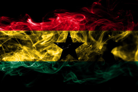 National flag of Ghana made from colored smoke isolated on black background. Abstract silky wave...