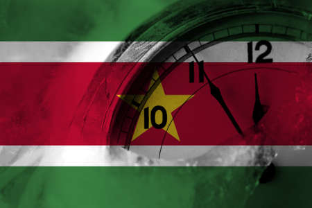 Suriname flag with clock close to midnight in the background. Happy New Year conceptの写真素材