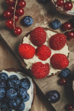 Berry tartlets on wooden table, look from above