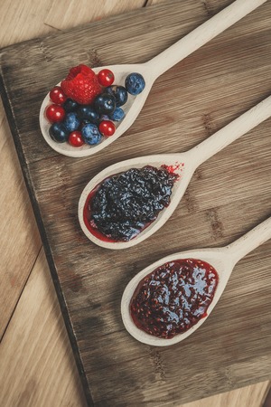 Wooden spoons with jams an berries on the wooden tableの写真素材