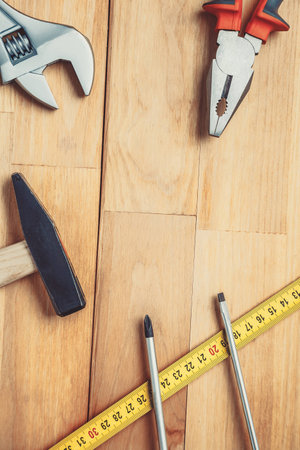 Pliers, screwdrivers, ruler on wooden desk, look from aboveの写真素材