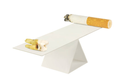 Cigarette and aching tooth on the scales on a white backgroundの写真素材
