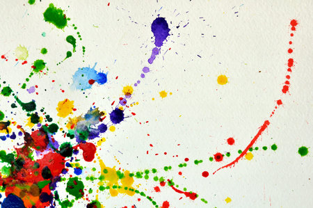 Drops colored watercolor paint randomly splattered on a sheet of white paper