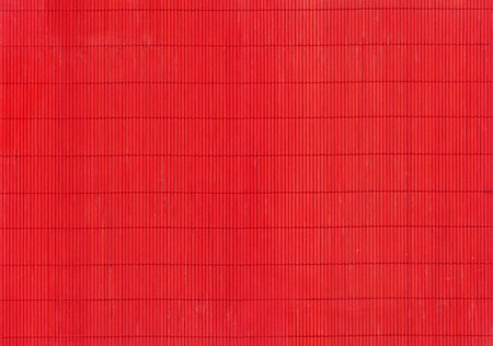 A fragment of the red mat of interwoven chips of bamboo as backgroundの写真素材