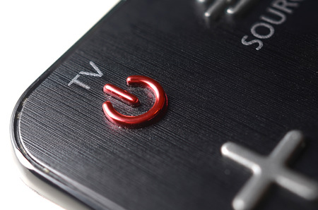 Red power button on the TV remote control on white backgroundの写真素材