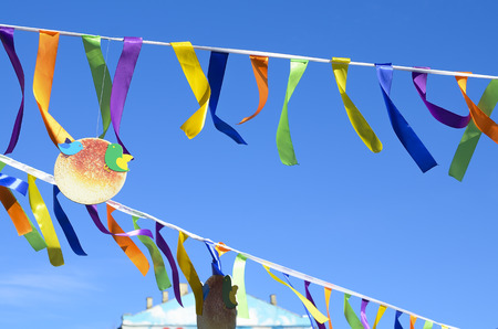 Multi-colored ribbons and pancake hanging from a rope against the blue sky.の写真素材