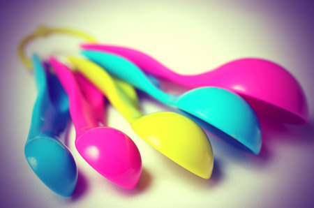 Kitchen colorful plastic measuring spoons on a white background. Close up view. Vintage toning.の写真素材