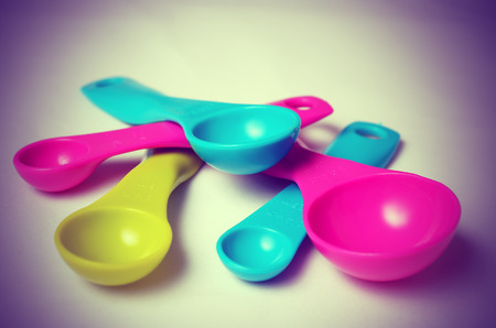 Kitchen colorful plastic measuring spoons on a white background. Close up view. Vintage toning.の写真素材