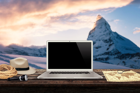 white laptop map hat rope torch on the table with winter mountains in the background mockup presentationの写真素材