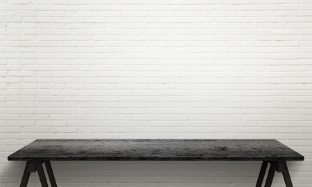 Black wooden table with legs. White brick wall texture in background.の写真素材