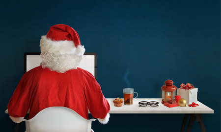 Santa Claus responds to letters on a computer for Christmasの写真素材
