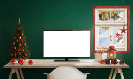 Computer display on table with isolated white screen for mockup in Christmas time. Christmas tree, gifts, decorations in background.の写真素材