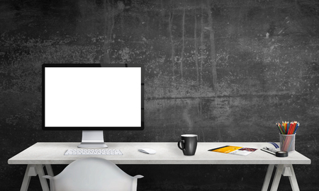 Isolated computer display for mockup in office interior. Work desk with keyboard, mouse, cup of coffee, paper, pencils. Free space on wall for text.の写真素材
