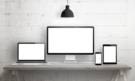 Responsive web site mockup. Computer display, laptop, tablet and smart phone on desk with isolated, blank, white screen for design presentation.の写真素材