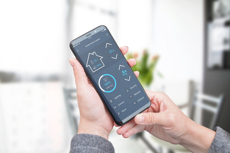 Woman use modern mobile app with modern flat design interface to control home security; lighting and air temperature.の写真素材