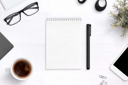 Empty writing pad on office desk surrounder with office supplies. Top view composition.の写真素材
