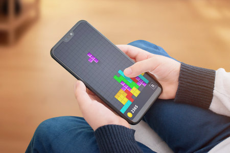 Popular tetris game on modern smart phone. Concept of technology development children intelligence.