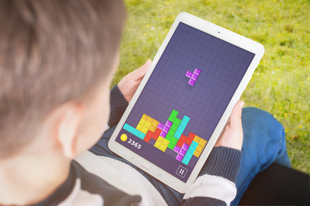 Child play popular gane on his tablet. Concept of developing children intelligence using computer games.の写真素材