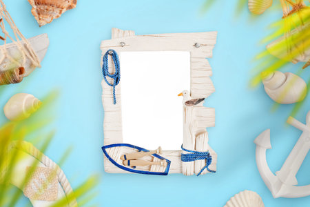 Photo frame on blue desk surrounded with smmer, travel, sea decorations.