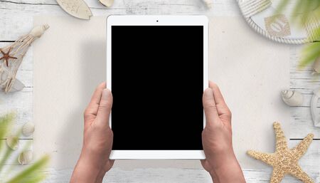 Tablet mockup in hands for travel app or web design presentation. Sea, summer vacation things in background.の写真素材