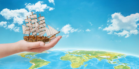 Hand holding the ship over the globe. Concept of traveling across the sea. Free space beside fot...