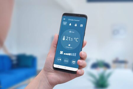 Modern climate control app interface on a smartphone in hand. Concept of simple temperature control and auto heating.の写真素材