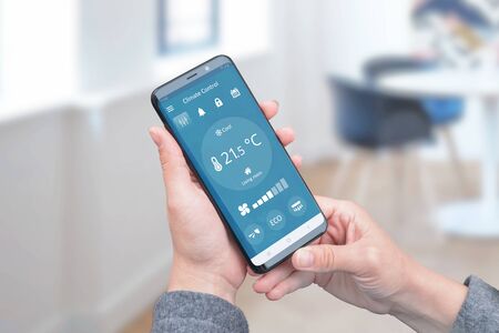Heat control in the house with simple app on phone for remote control of air conditioners. The concept of energy efficiency, savings and ecology.の写真素材