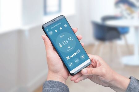 Heat control in the house with simple app on phone for remote control of air conditioners. The concept of energy efficiency, savings and ecology.