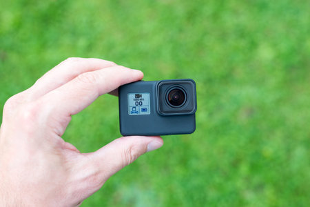 Action camera in hand close-up. Lens and small display with resolution, battery and memory card...