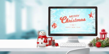 Mery Christmas on computer display and decorations on work desk. Copy space beside. Computer display mockup.の写真素材